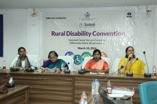 From left to right - Durgashri, Smt. Katsuri Mohapatra, Jharana, and Nidhi. She is speaking into a mic. There is a banner with the event details behind them – Rural Disability Convention, National Career Service Centre for Differently Abled, Bhubaneswar, March 10, 2026 and organisers’ logos on top.