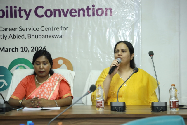 Close up of Nidhi speaking into a mic. Next to her is Jharana Mallick.