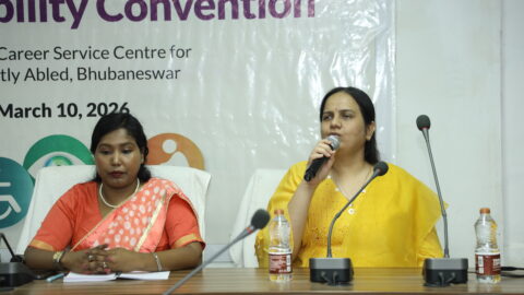 Nidhi Goyal speaking into a mic on a panel. Jharana Mallick is sitting next to her.