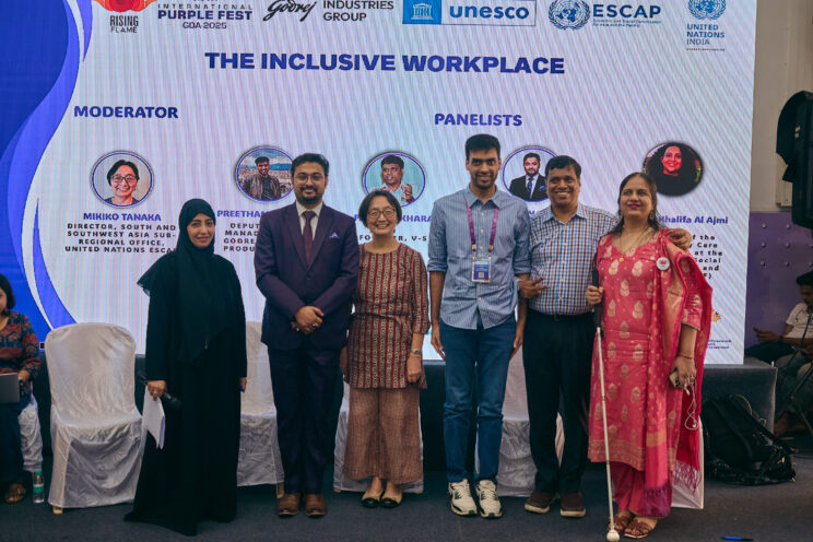 All speakers and moderators standing in front of the screen with Nidhi.