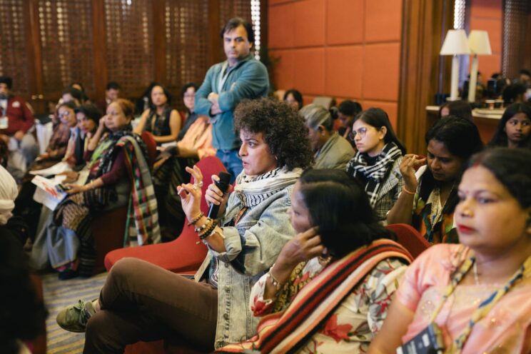 One of the audience members speaking into a mic at the 'Deconstructing Ableism' teach-in. She has short curly hair and is wearing a light denim jacket.