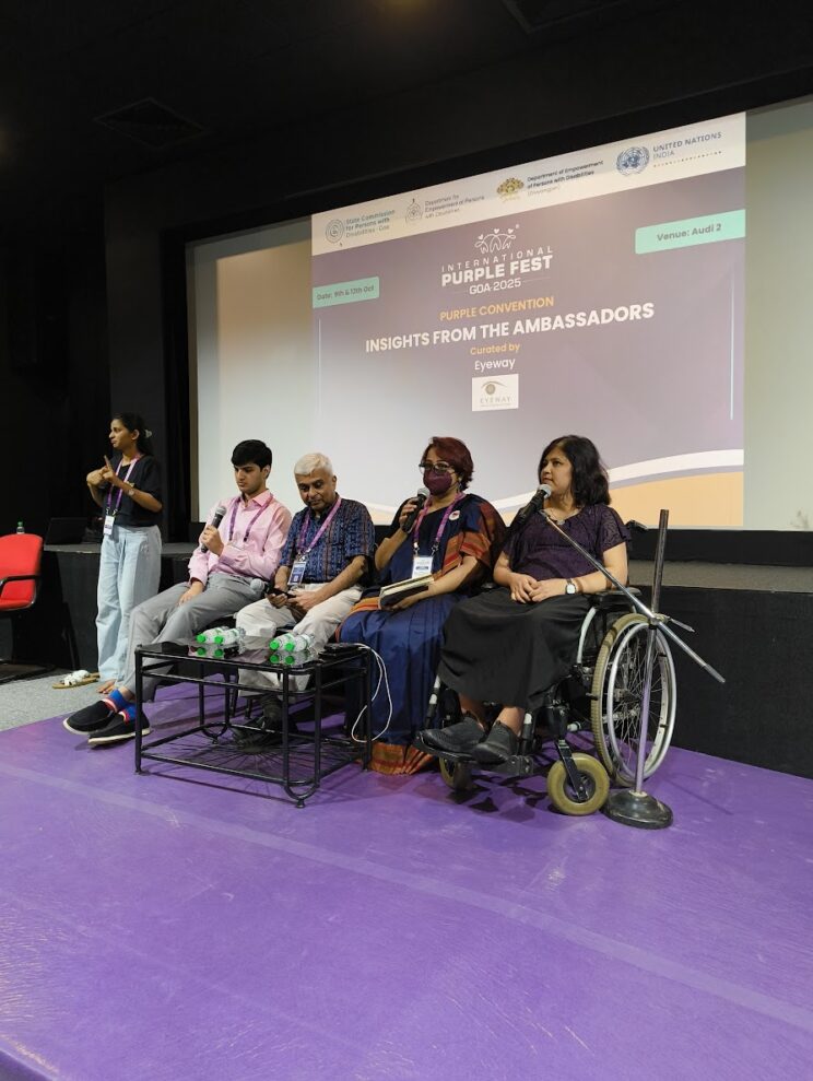 A panel of speakers are sitting in front of a stage and projector with the session name on it - Insights from the Ambassadors curated by Project Eyeway. From left to right - Pranav Bakshi, George Abraham, Srinidhi Raghavan, Swarnalatha J. Srinidhi is speaking.