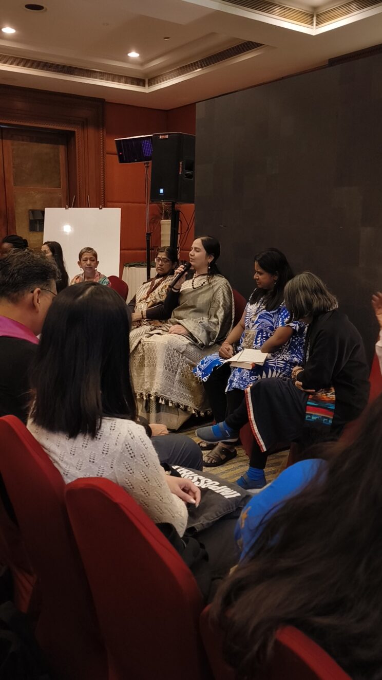 Nidhi speaking during the first session of the day. She is sitting, wearing a silver saree. Niluka and Renu are on her left and Shampa and Rupsa are on her right.