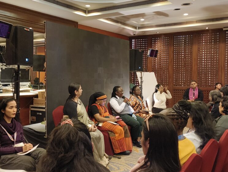 Nidhi is sitting with panellists from left to right - Shamim, Loretta, Pyllis and a sign language interpreter at the end. Loretta is speaking into a mic while the others listen.
