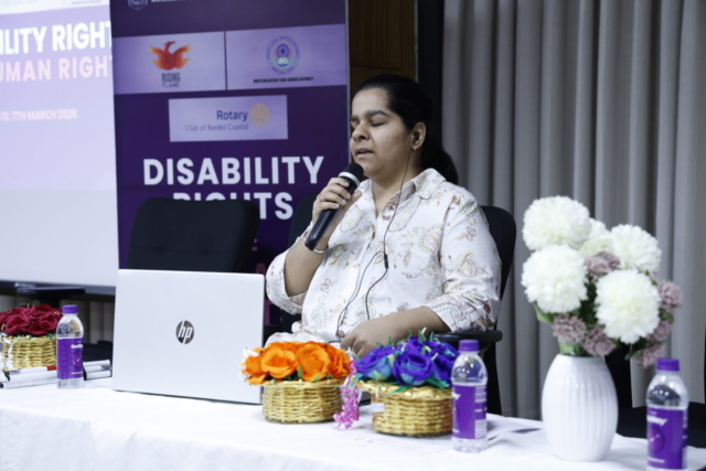 Anchal Bhatheja sitting on a chair, with a laptop in front of her, speaking into a mic