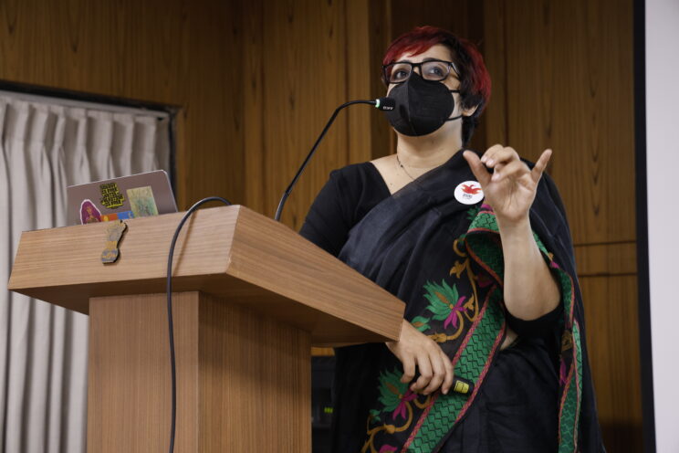 Srinidhi Raghavan at a podium, speaking into a mic