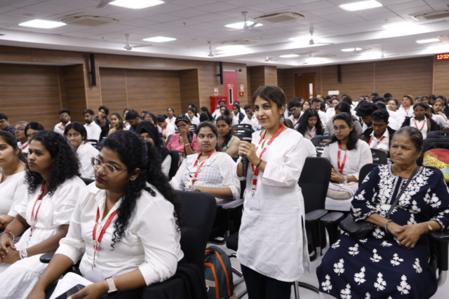 A student in the audience standing and speaking into a mic while others listen.
