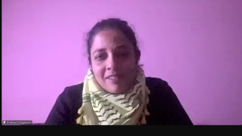 Dr. Prathama Raghavan is pinned on the screen. She is sitting in front of a purple/pink wall. She is wearing a black long-sleeve top and has a keffiyeh wrapped around her neck. Her hair is tied back.