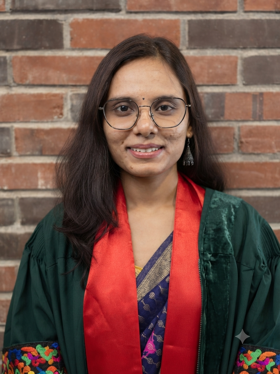 Arti Vilas Manmode is an Indian woman with long dark hair. She is wearing glasses. She is wearing a dark green robe with a red border over a blue saree.